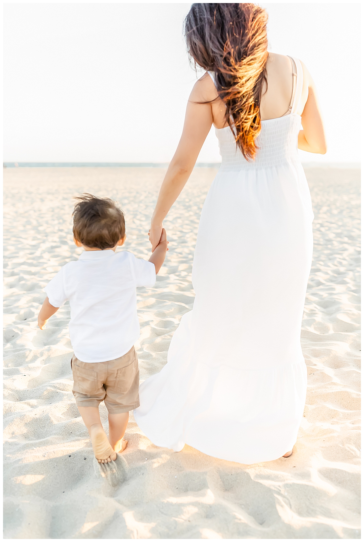 mom walking son on beach and holding hands