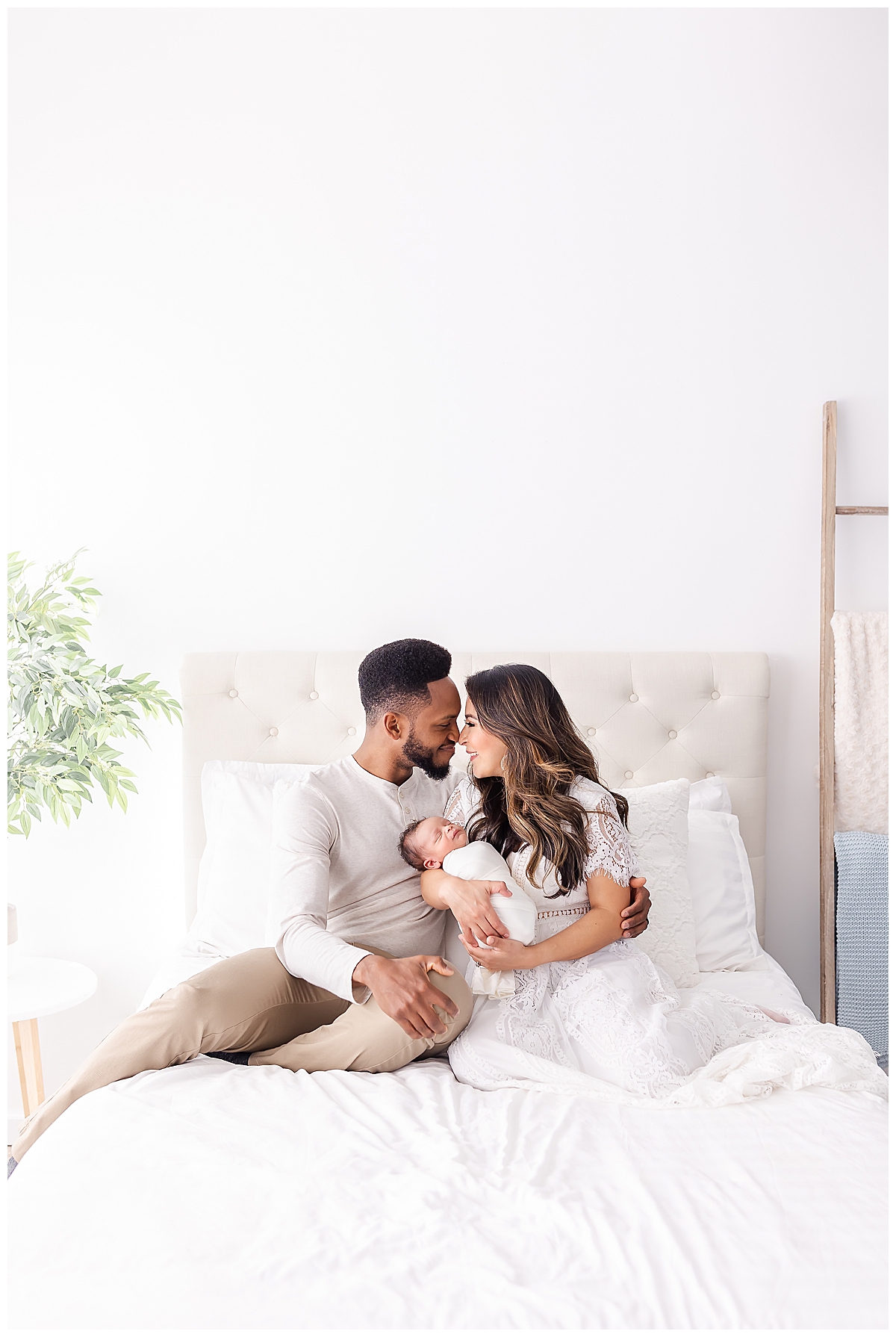 Mom and Dad holding newborn on bed