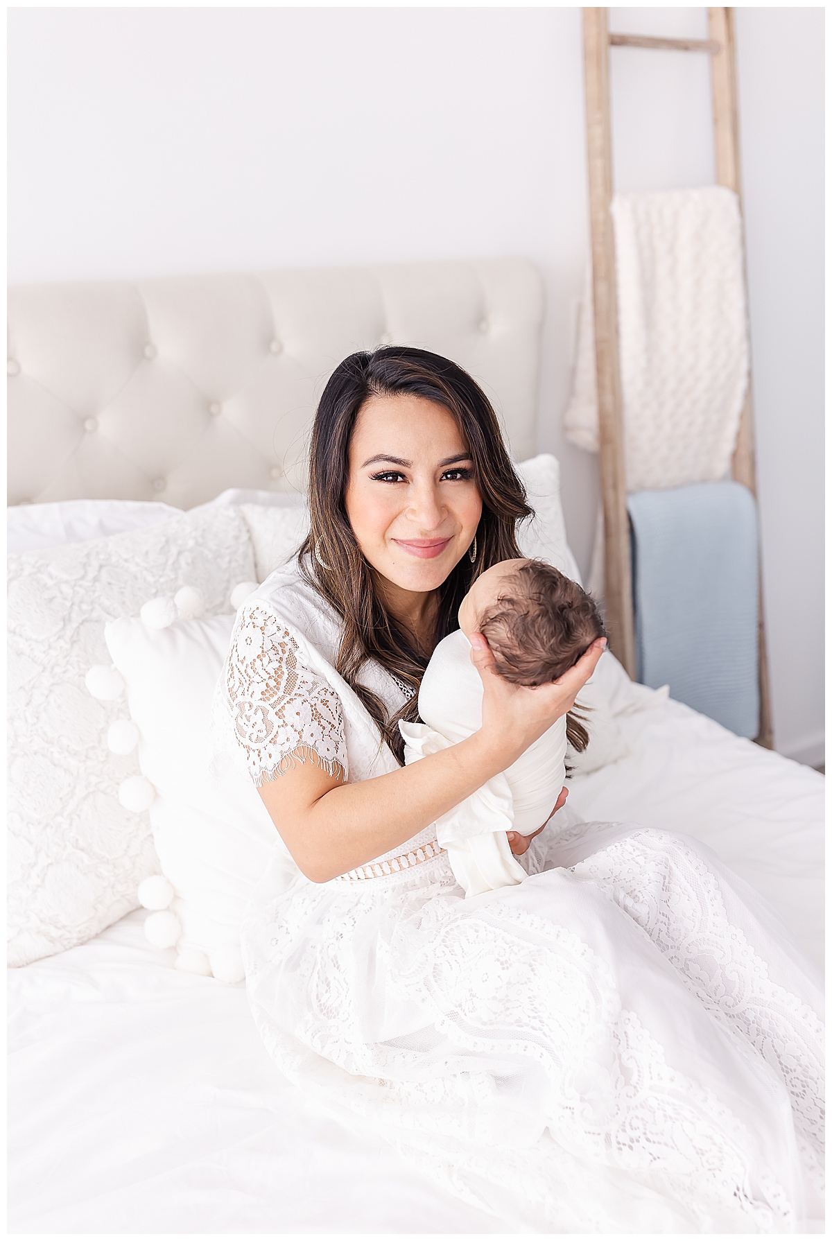 Newborn held by mom on white upholstered bed