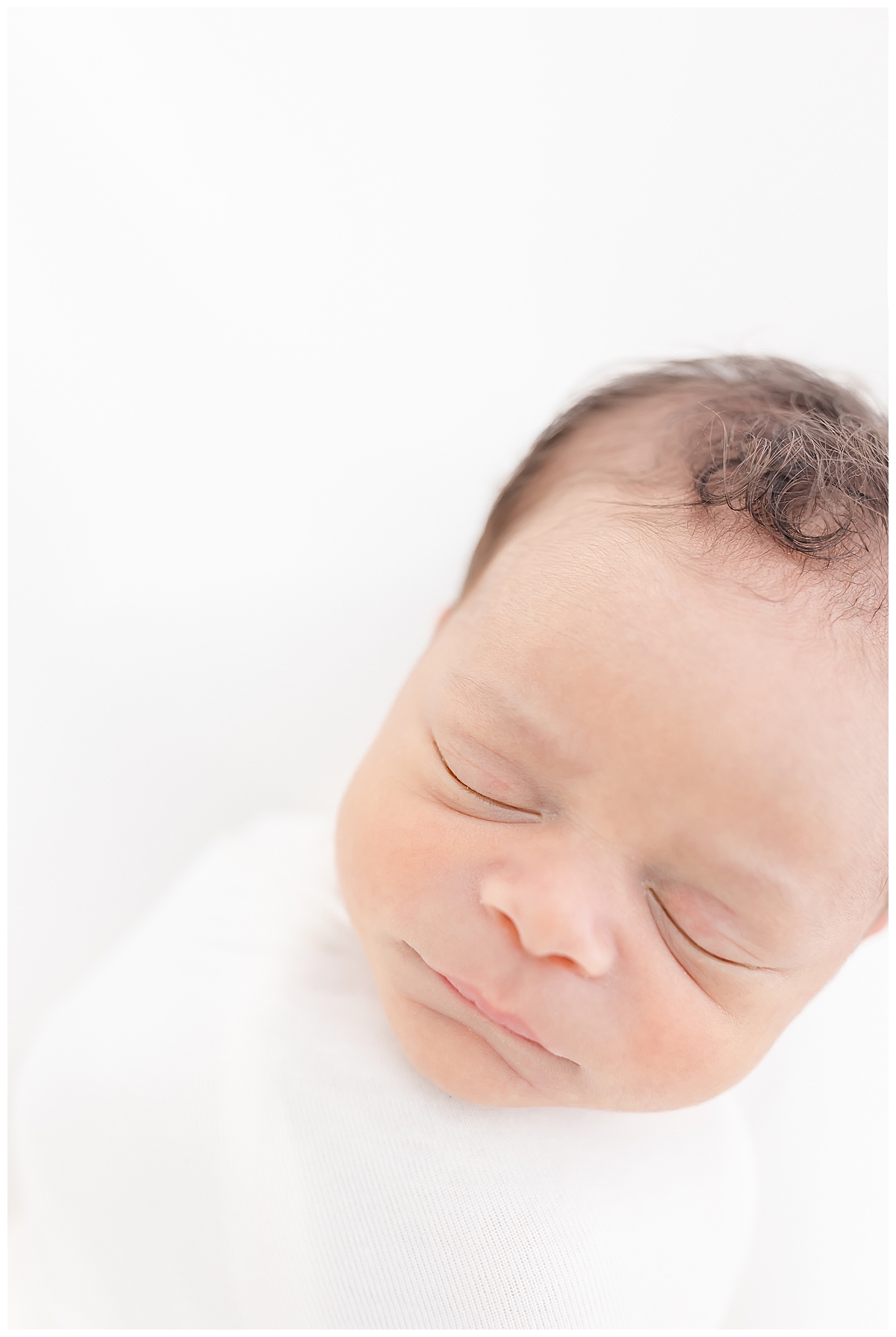 Newborn wrapped in white swaddle
