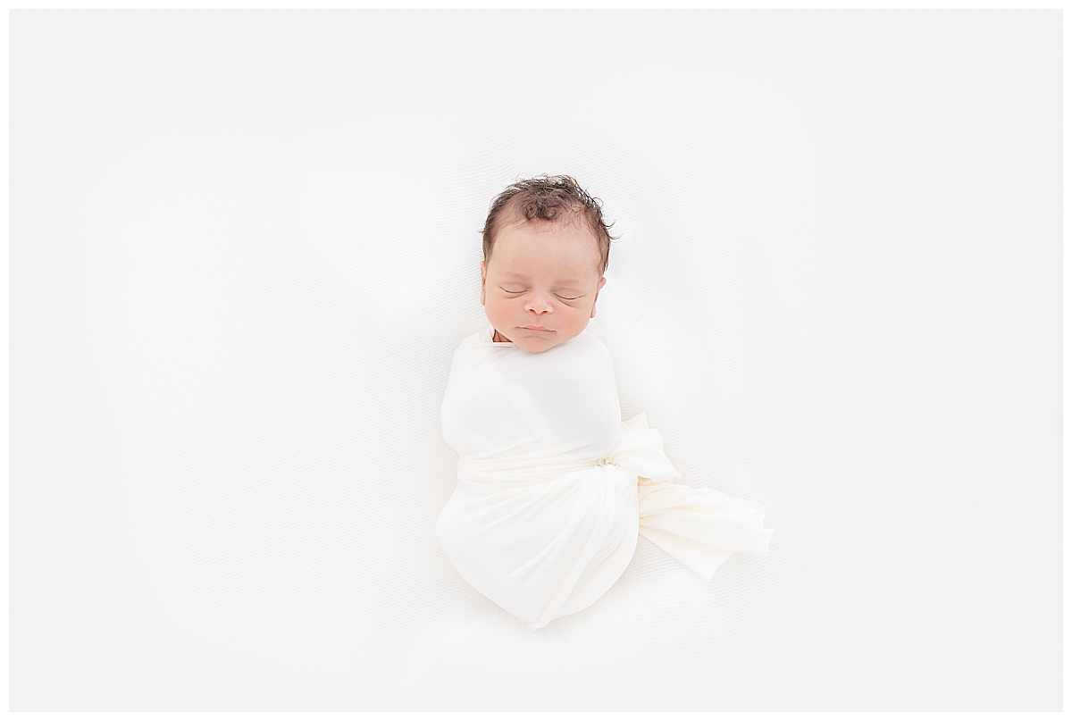 Newborn swaddled in white blanket 