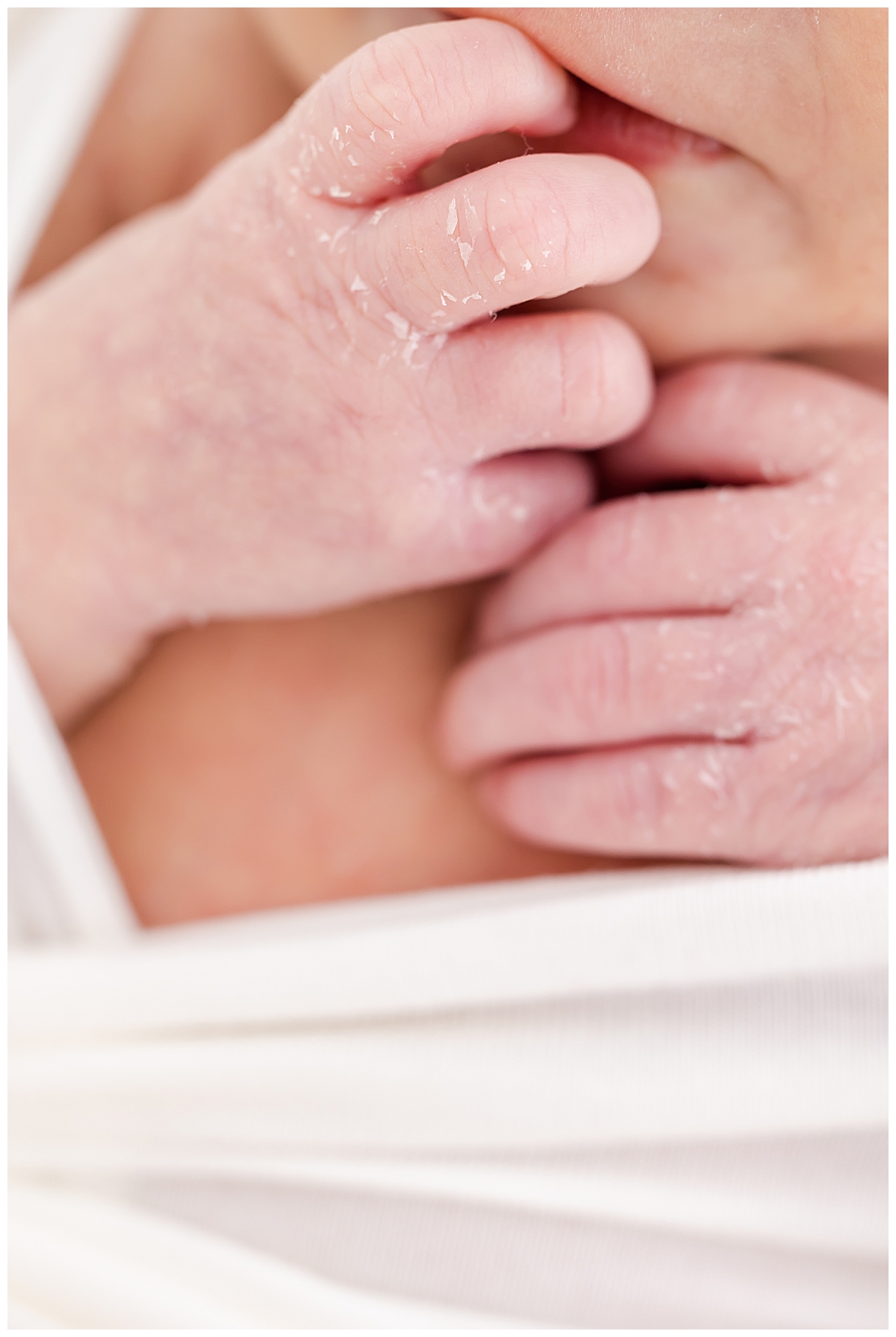 Newborn wrapped in white swaddle with close up of hand details
