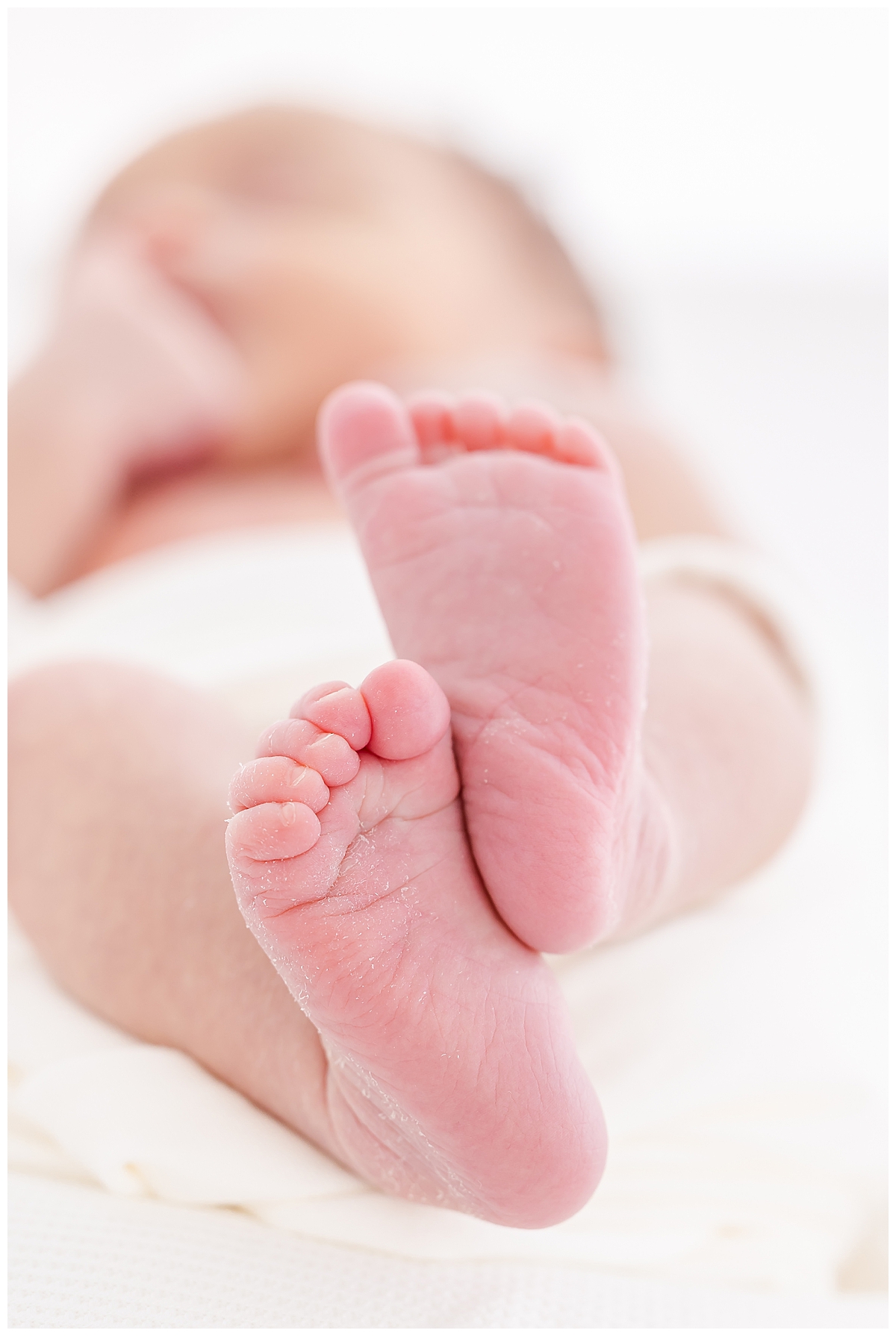 Newborn wrapped in white swaddle with close up of feet details