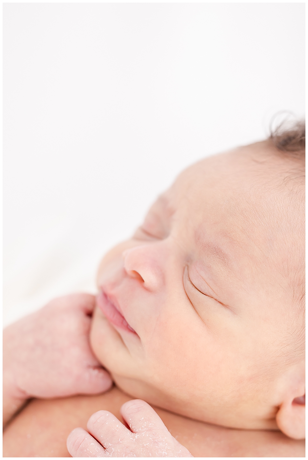 Newborn wrapped in white swaddle with close up of face details