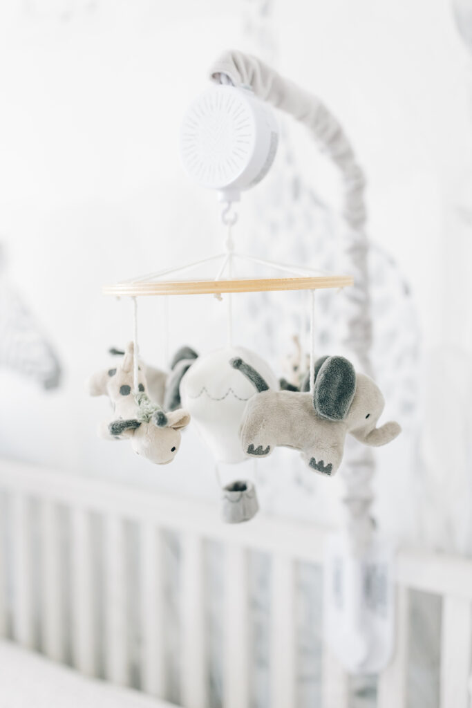 A close-up detail of the nursery crib mobile in a grey and white jungle themed nursery.  