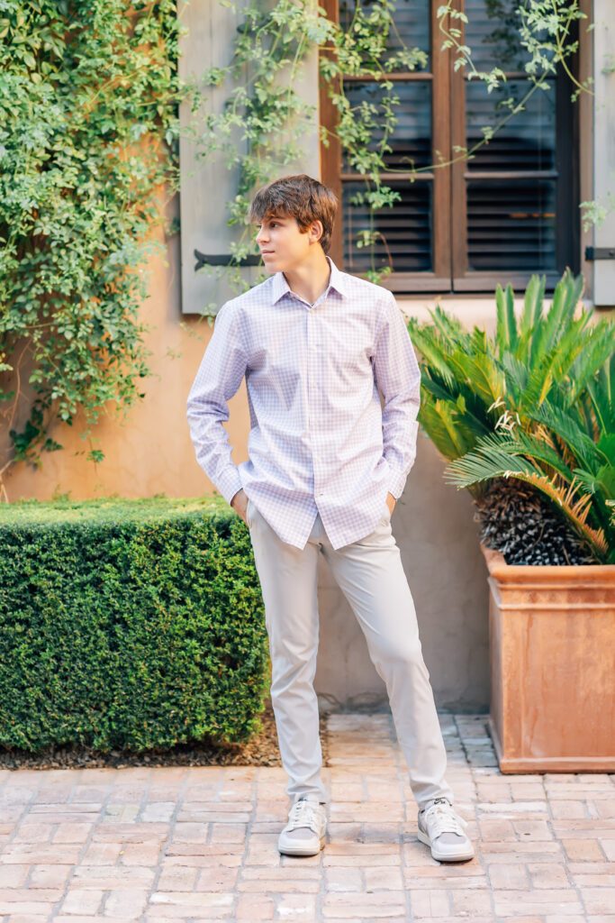 Notre Dame Prep High School Senior in Scottsdale, AZ standing in the courtyard at Silverleaf Country Club wearing a purple shirt and khaki pants smiling to the left of the camera. 