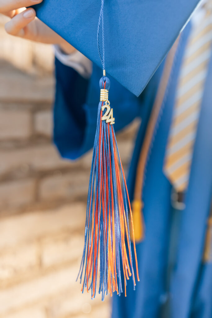 High school senior holding his blue graduation cap with a red and blue tassel with the number 24 in gold. 