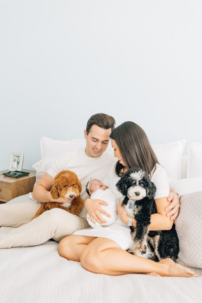 A heartfelt image from Nest: A Luxury Maternity & Newborn Workshop showing new parents and their two doodles welcoming baby with warmth and connection.