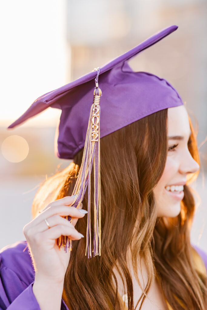 What to wear for senior pictures for girls – Scottsdale senior wearing a pastel floral mini dress and strapped wedges with cap, gown, and stole for downtown senior photos